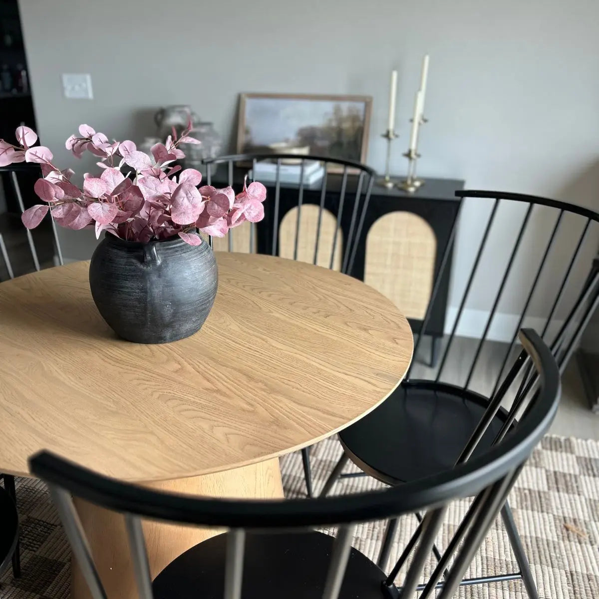 Saigong Oak Round Dining Table with black chairs, neutral wall, and patterned flooring in dining room.