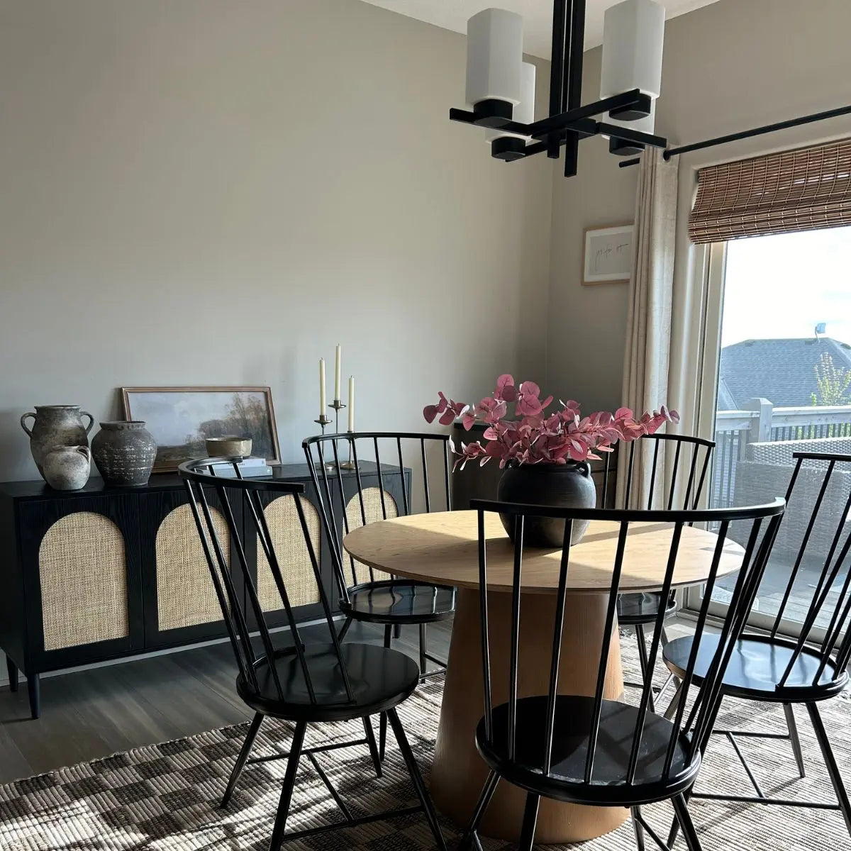 Saigong Oak Round Dining Table in a modern dining room with black chairs and wood flooring.