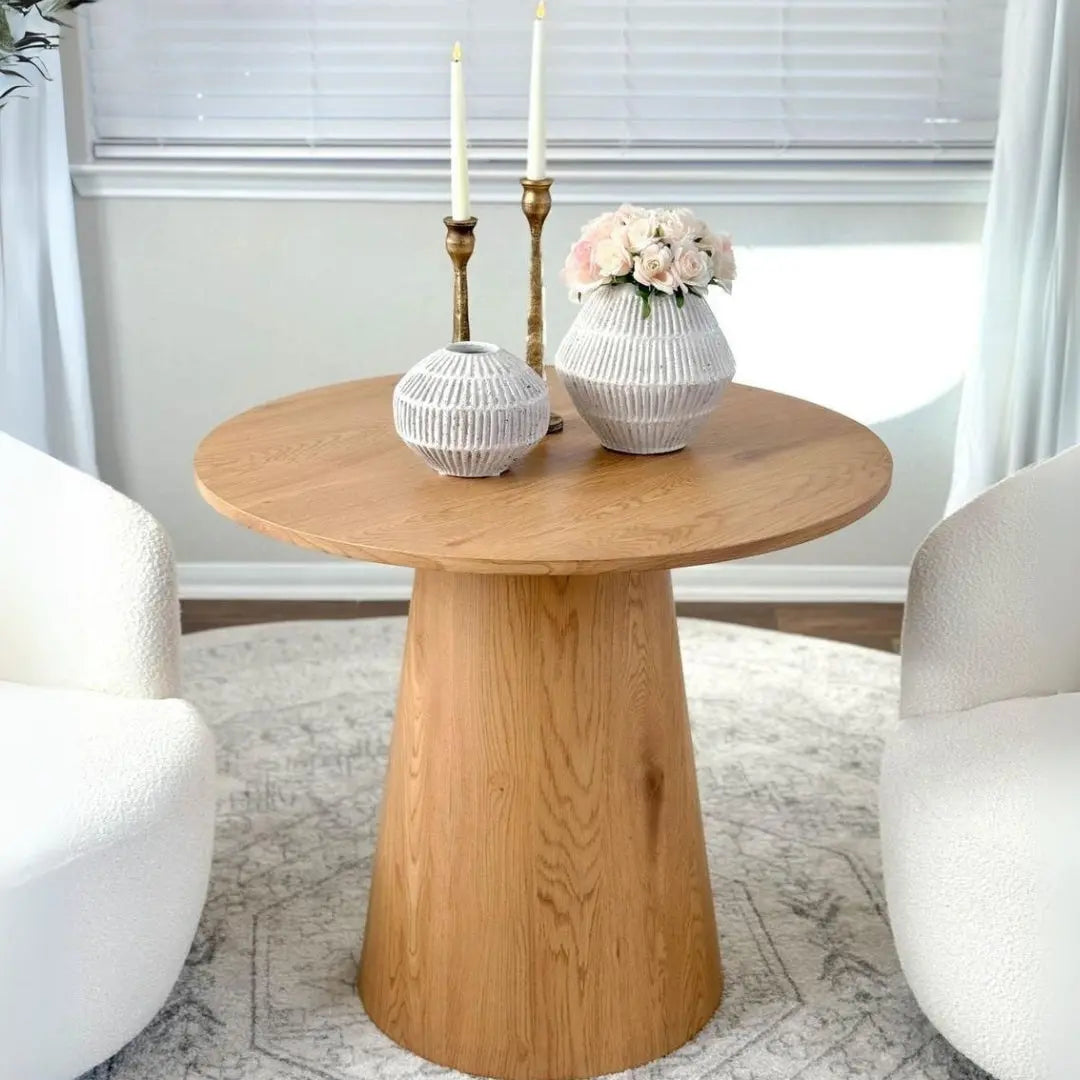 Dwen Modern Round Pedestal Dining Table with white chairs, grey rug, light walls in dining room.