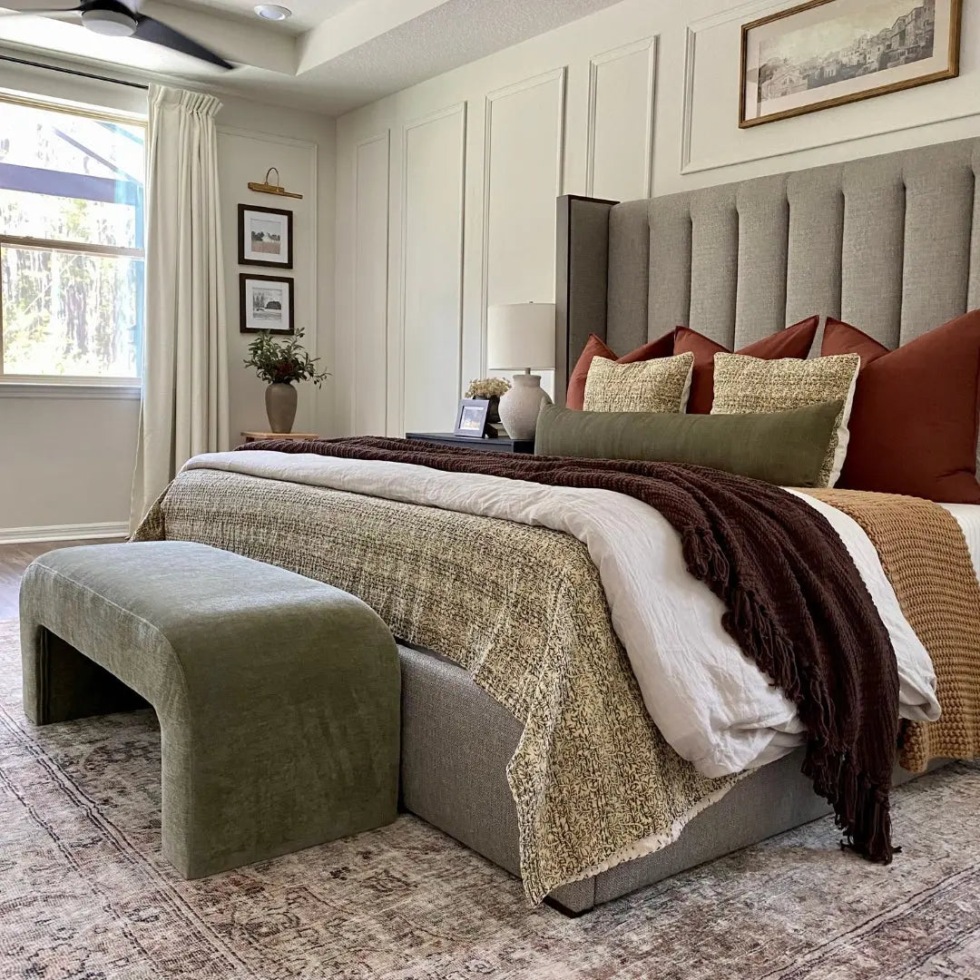 Bedroom with green Lily Chenille Accent Waterfall Bench, gray upholstered bed, cream walls, wooden flooring.