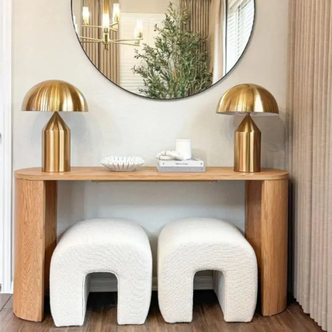 Dwen Modern Oval Console Table with gold lamps, white ottomans, in cozy living room setting.