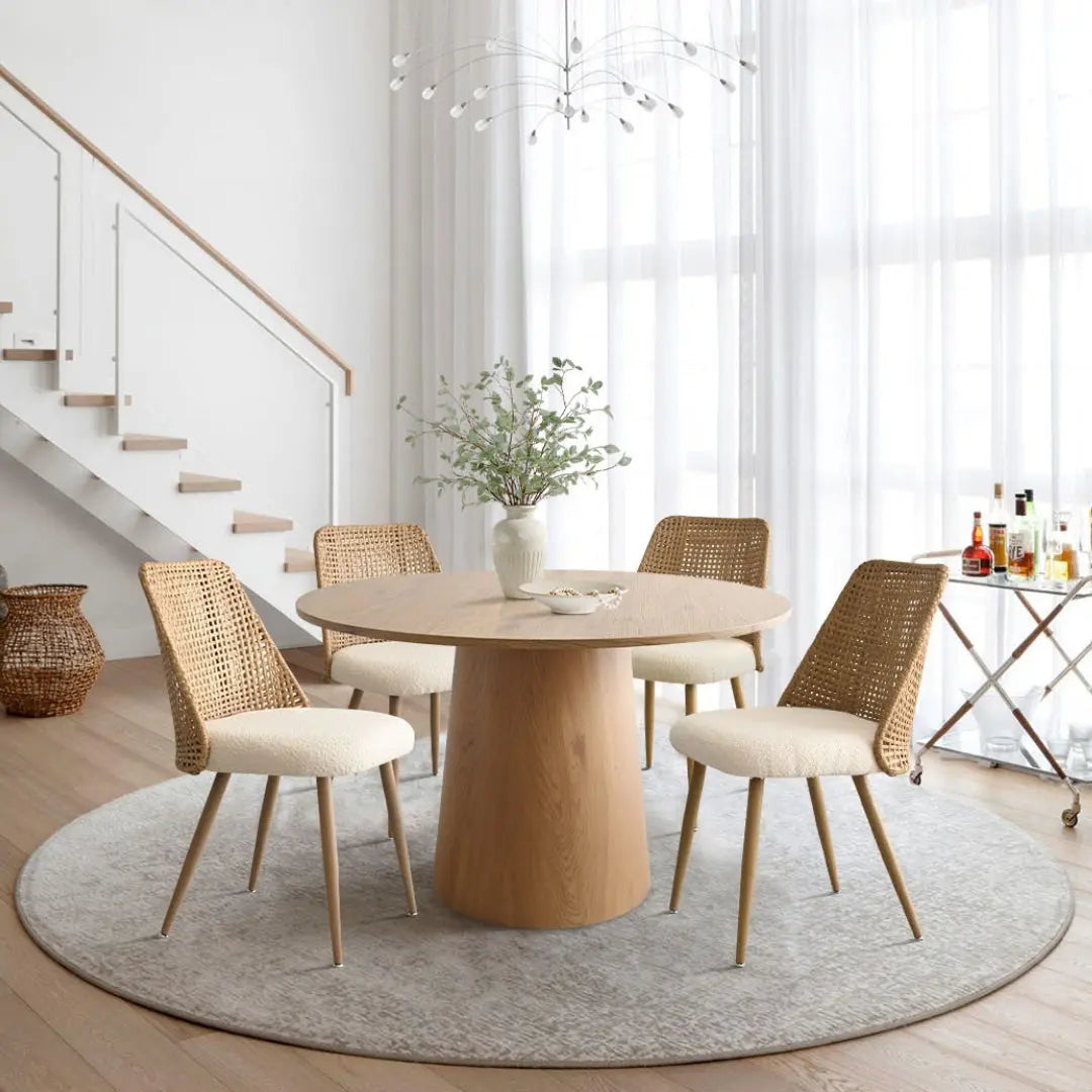 Nice Rattan upholstered dining chairs in modern airy room with round table, light wood floors.