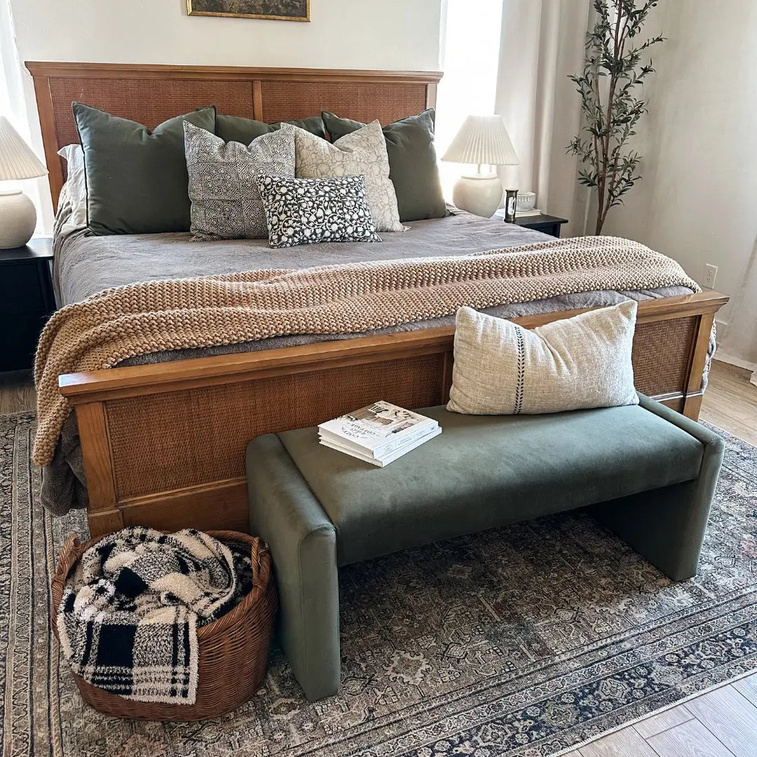 Kaia Modern Leather & Velvet Waterfall Bench in bedroom with wooden bed, gray bedding, woven basket.