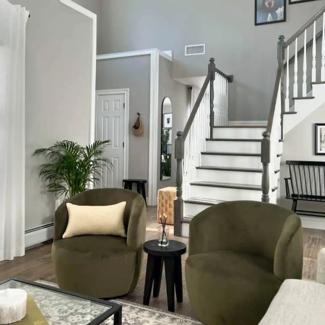 Bella Modern olive green velvet swivel barrel chair in elegant living room with staircase and decor.