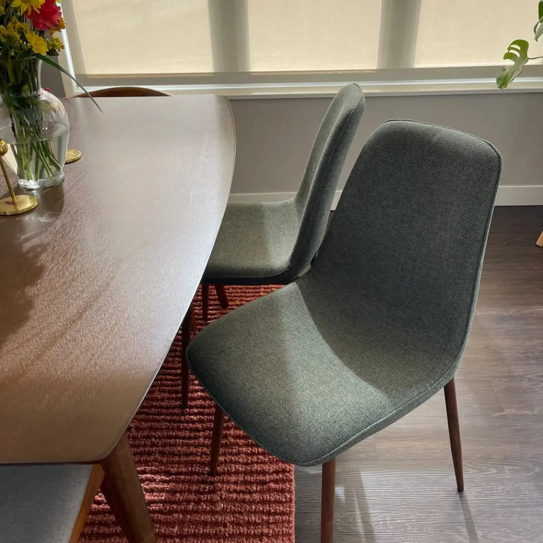 Oslo Modern Upholstered Dining Chair with Walnut Legs, dark table, red rug, hardwood flooring.