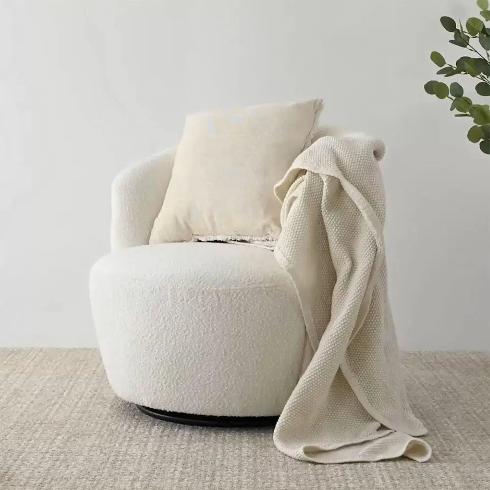 Bella Modern White Boucle Swivel Barrel Chair with throw, on neutral carpet in minimalist setting.