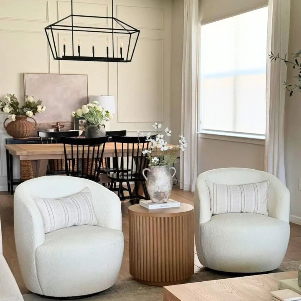 Bella Modern White Boucle Swivel Barrel Chairs in elegant dining room with wood table, black chairs.