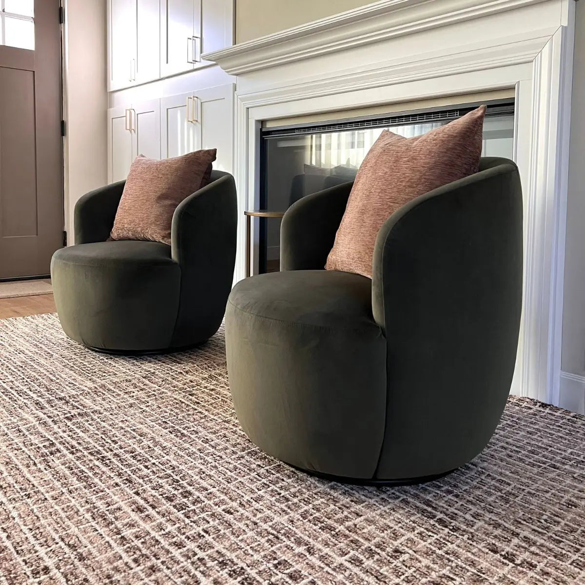 Bella Modern olive green velvet swivel barrel chairs in cozy living room with fireplace and textured rug.