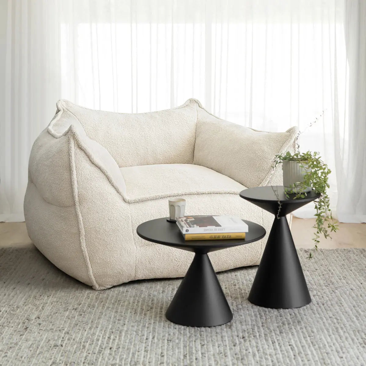 Boring Upholstered Teddy Fabric Bean Bag Chair with black tables on textured gray rug in living room.