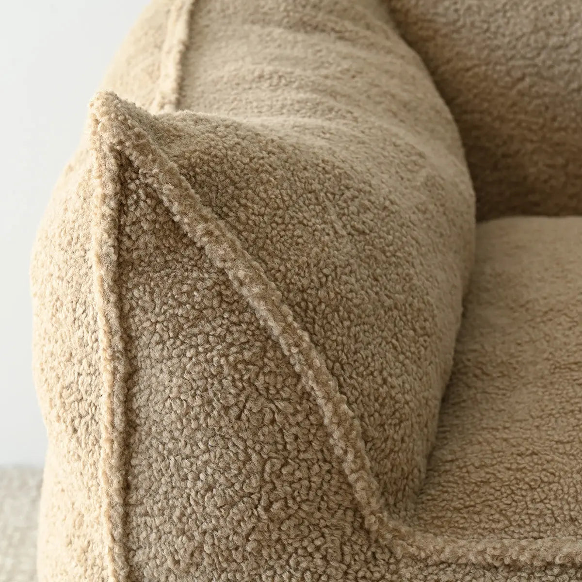 Close-up of textured beige Boring Teddy Bean Bag Chair corner; cozy detail in living room.