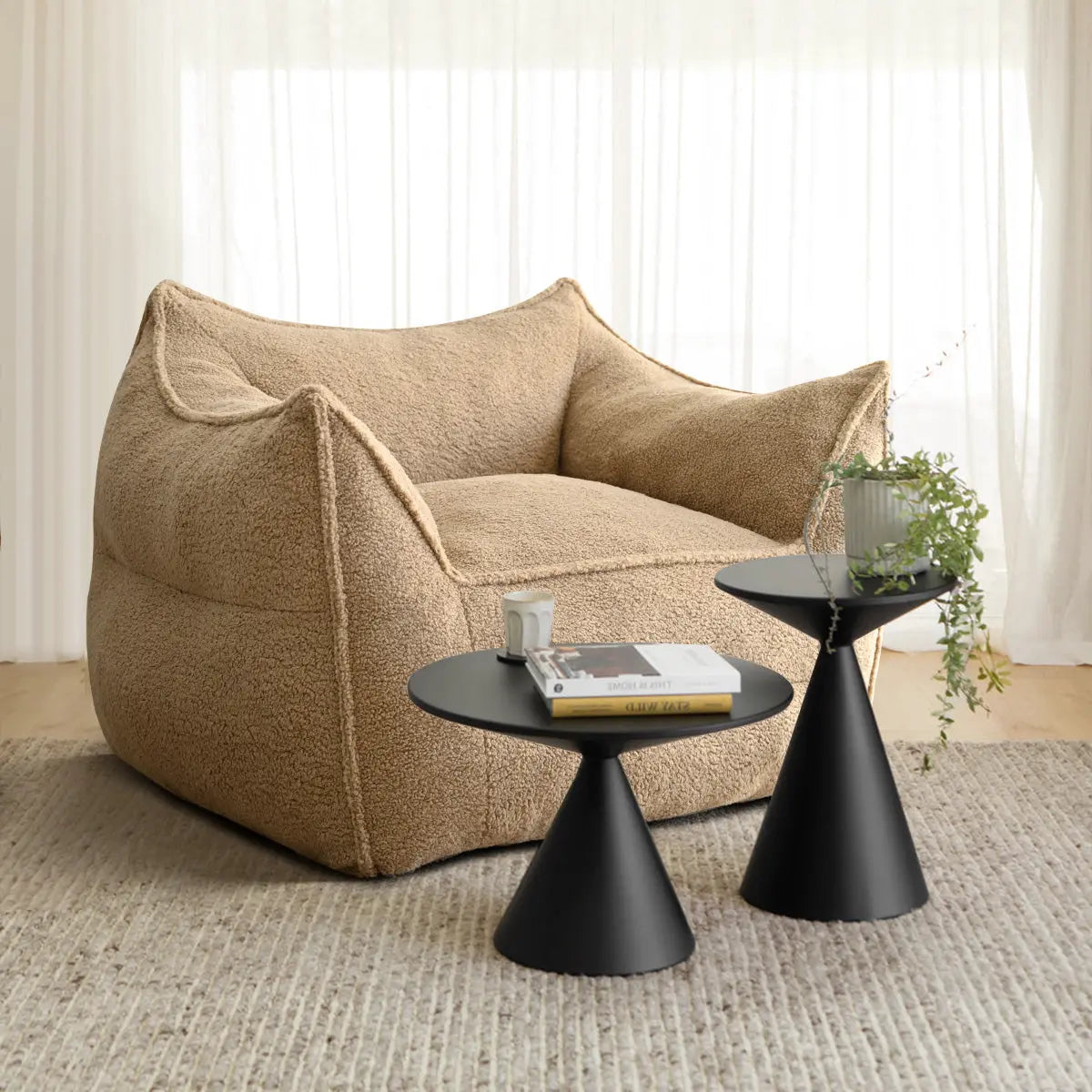 Boring Upholstered Teddy Bean Bag Chair with black side tables, beige rug, and sheer curtains.