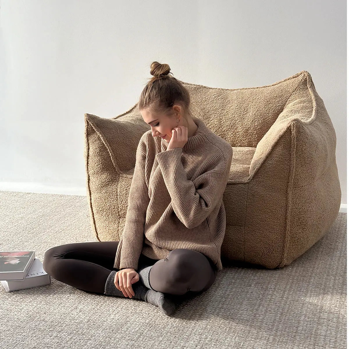 Woman sitting by Boring Upholstered Teddy Fabric Bean Bag Chair, neutral carpet flooring, white wall.