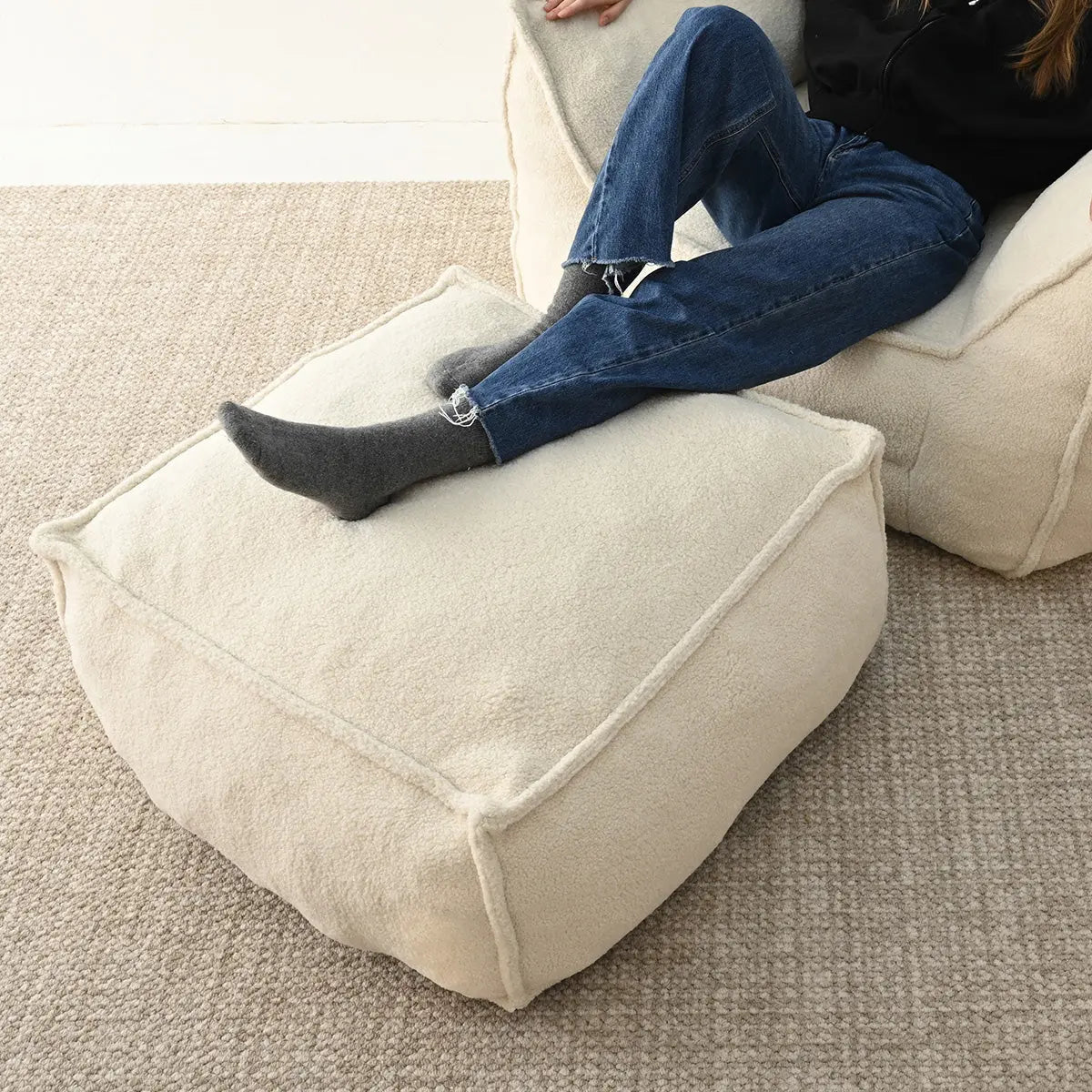 Bean bag chair and ottoman set on textured carpet, cream color, casual contemporary living room.