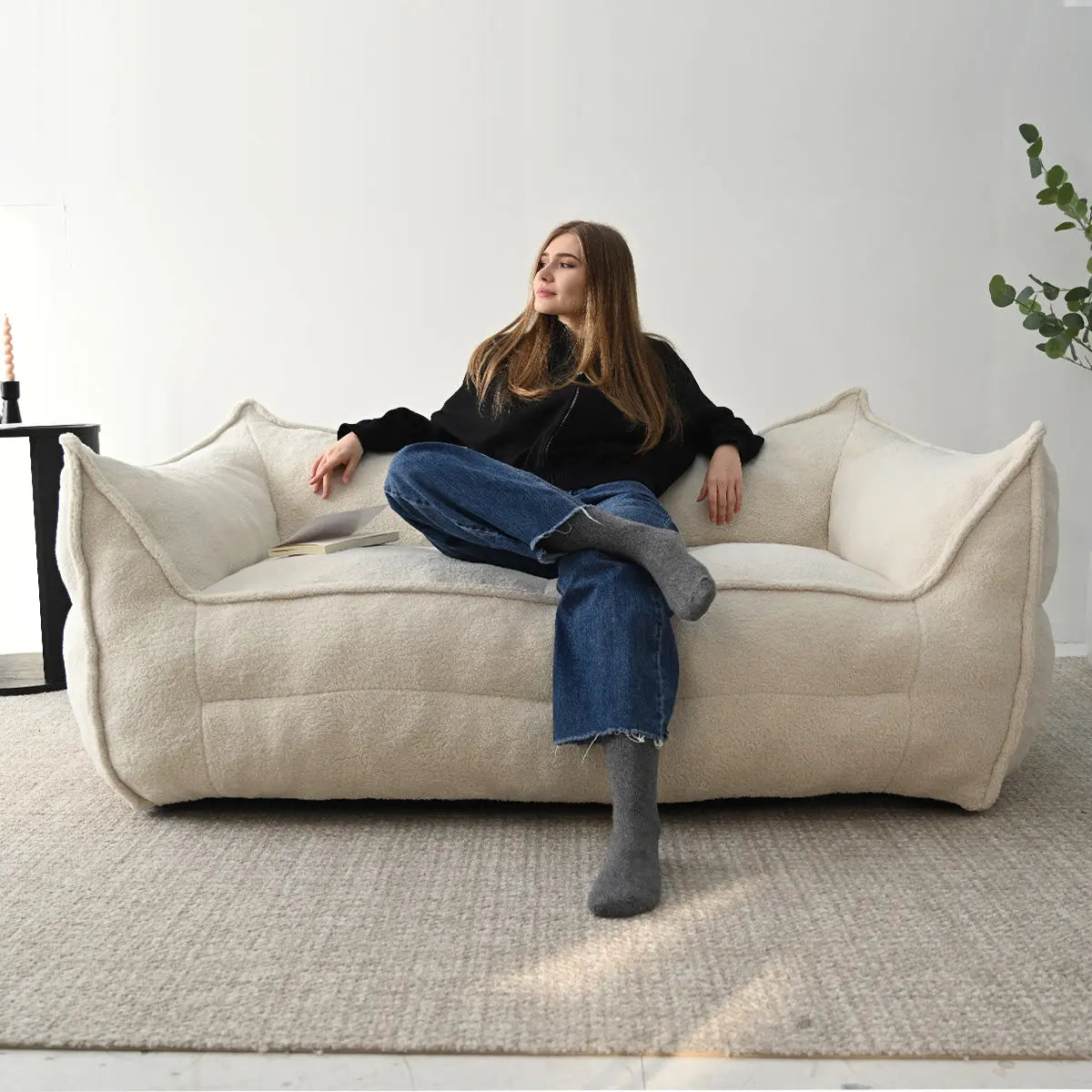 Luxurious white bean bag chair in living room with textured rug, black table, and greenery.