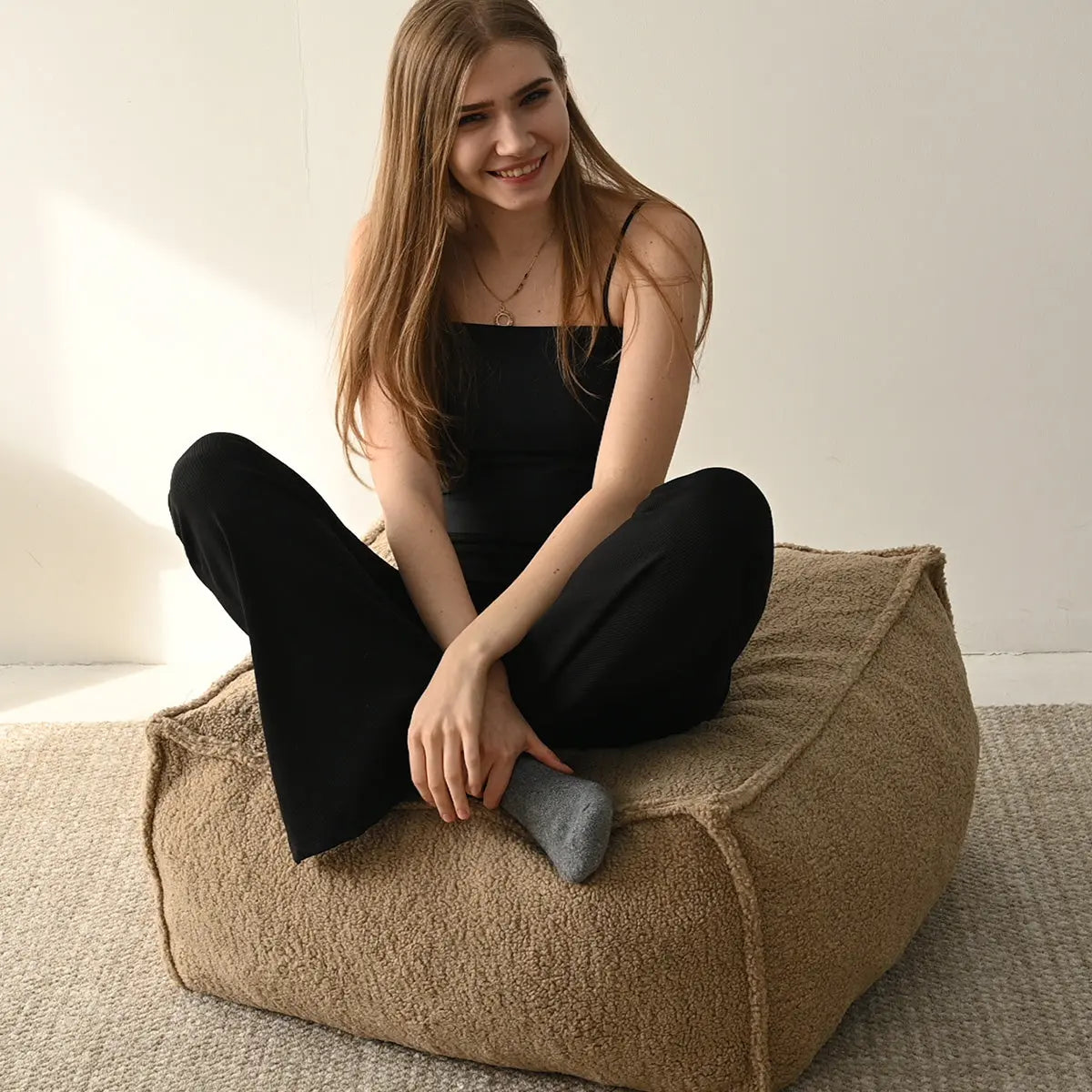 Boring Teddy Fabric Bean Bag Chair in beige, sitting woman, neutral carpet, minimalist room decor.