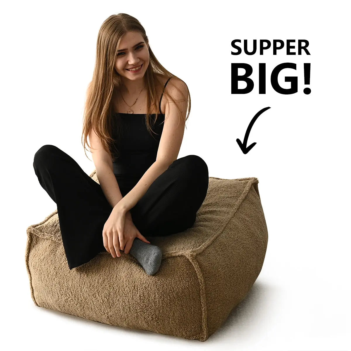 Woman sitting on oversized, beige Boring Teddy Fabric Bean Bag Ottoman with text indicating large size.