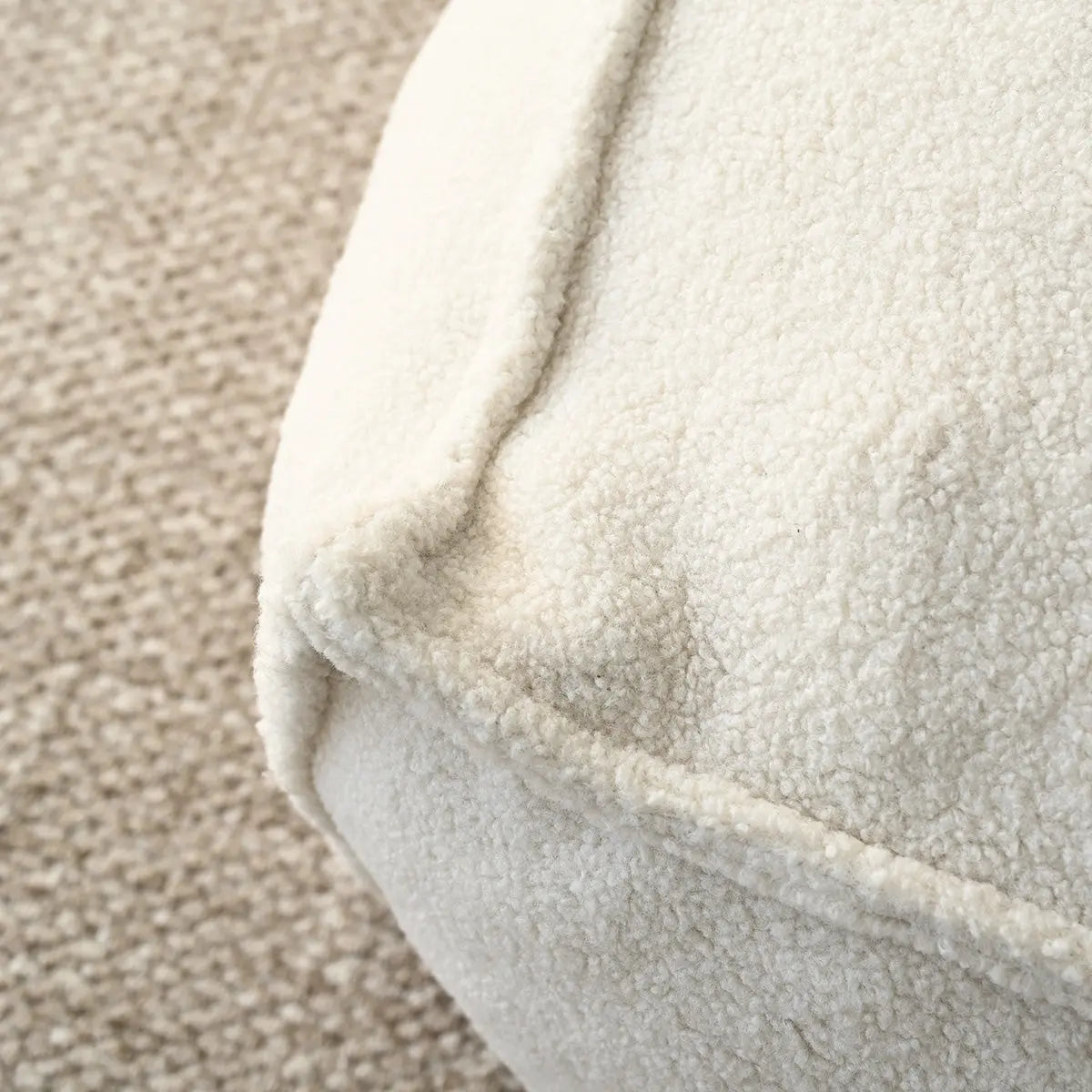 Close-up of Boring Teddy Fabric Square Bean Bag Ottoman on textured flooring, beige color.