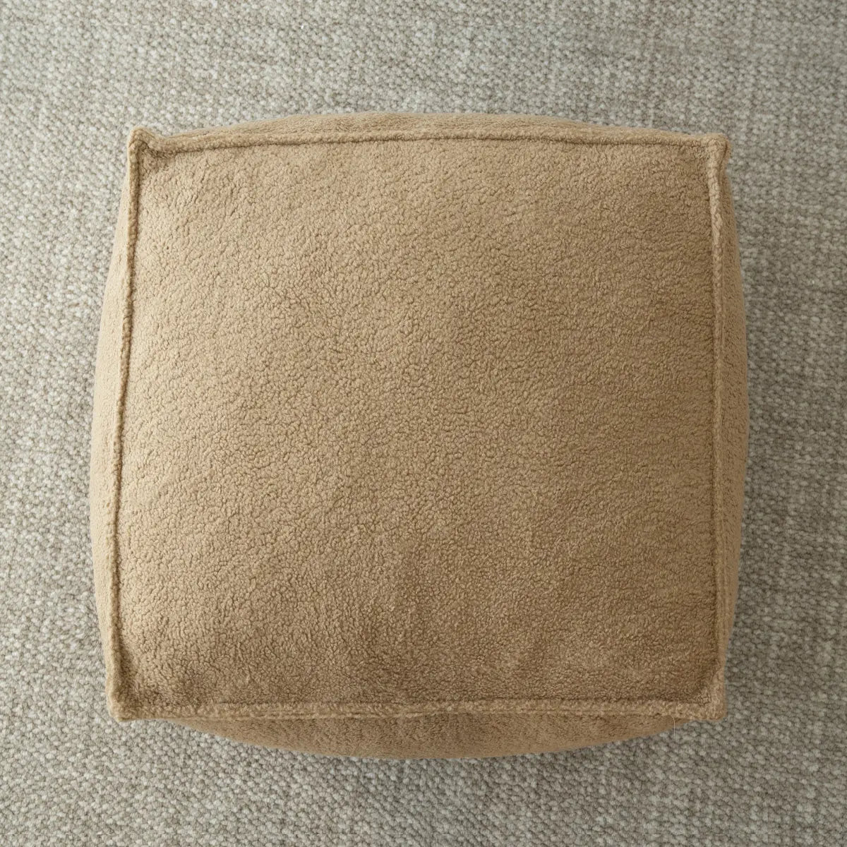 Boring Teddy Fabric Square Bean Bag Ottoman on textured carpet in living room.