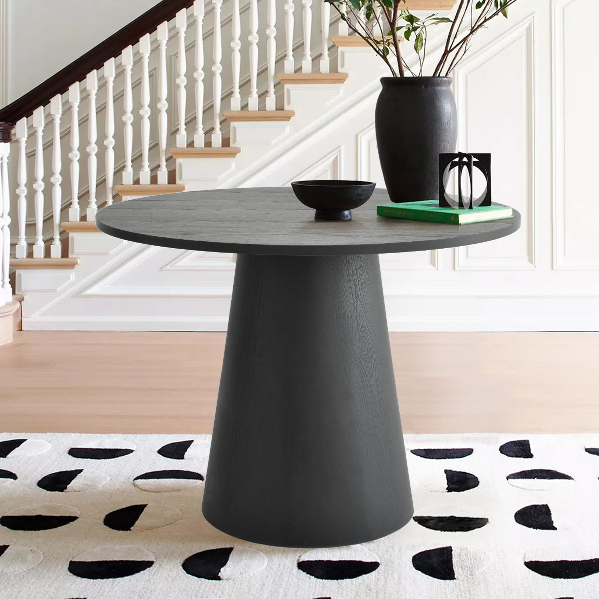 Dwen Modern Round Pedestal Console Table, staircase backdrop, light hardwood floor, black and white rug.