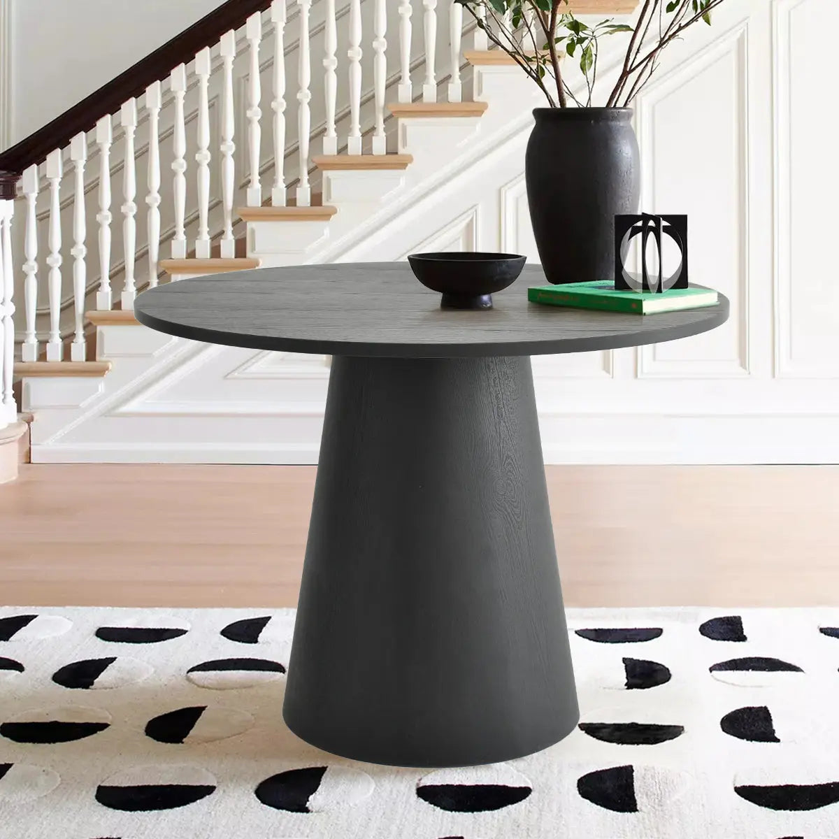 Dwen Modern Round Pedestal Table in stylish dining room with staircase, light wood flooring, abstract rug.