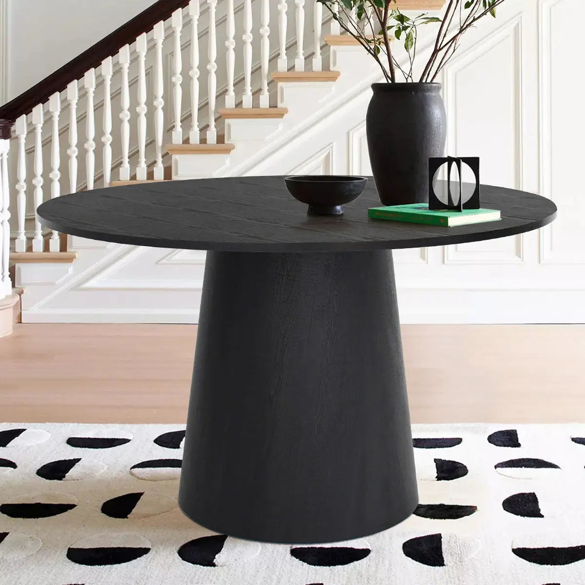 Dwen Round Pedestal Dining Table in modern room with wooden flooring and patterned rug.