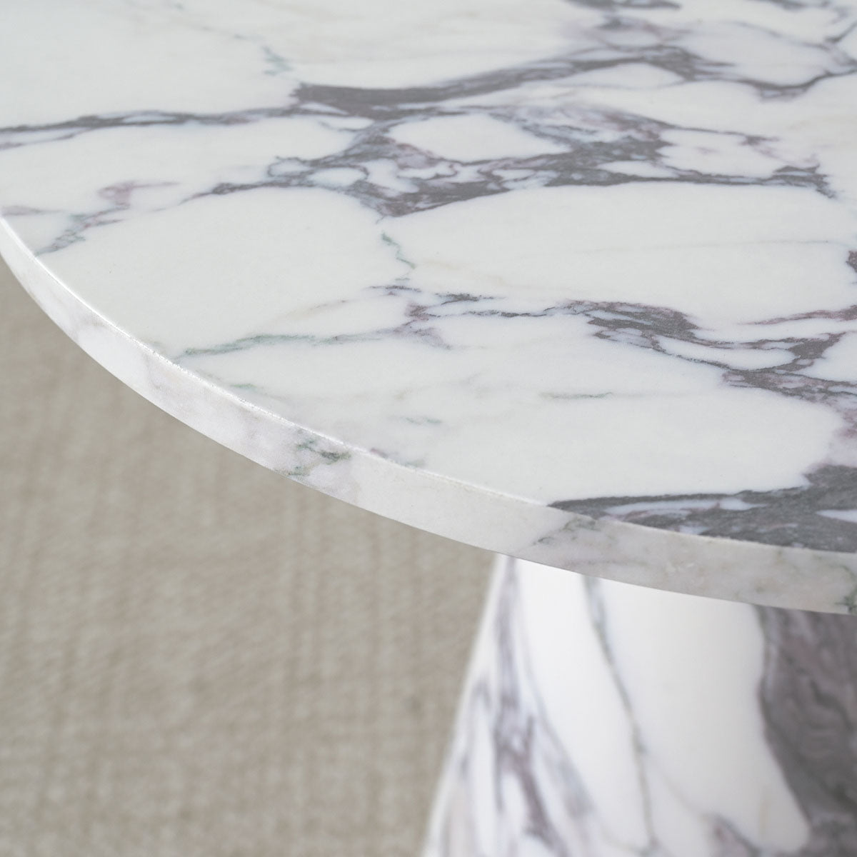 Close-up of Dwen Marble Round Pedestal Side Table on beige carpet, showcasing exquisite marble pattern.