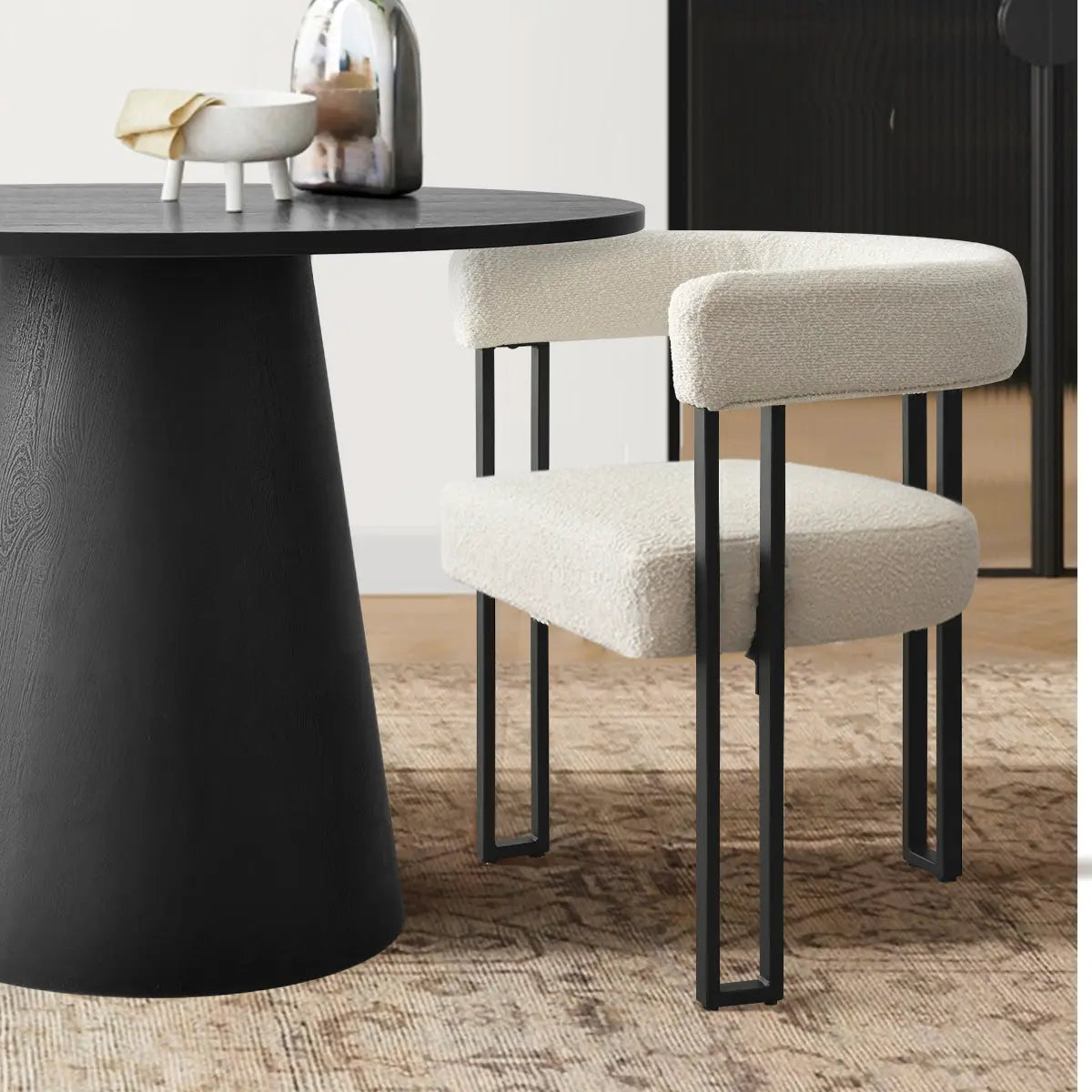 Dwen & Mia round dining set featuring black table, beige chairs, textured rug, in dining room.