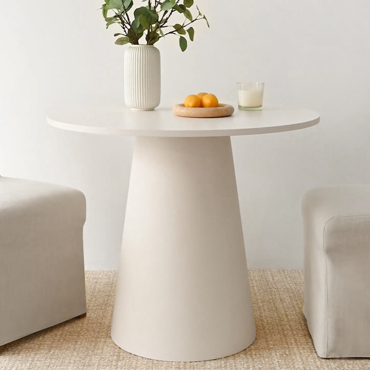 Dwen Modern Round Pedestal Dining Table with beige fabric chairs, light woven flooring in living room.