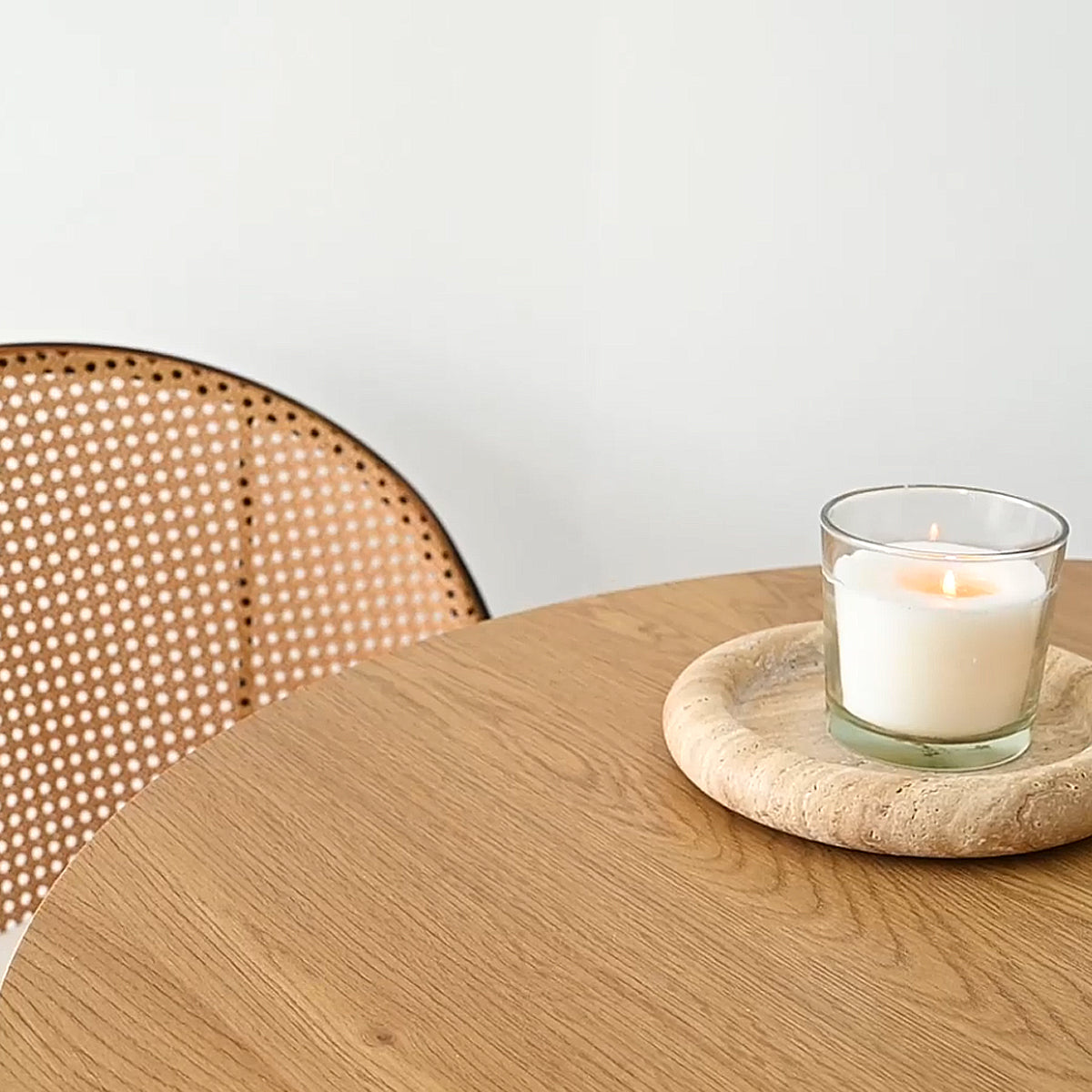 Dwen Modern Round Pedestal Dining Table with cane chair and neutral wall background in dining room.