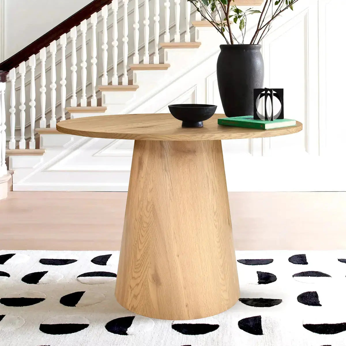 Dwen & Edwin dining table set in modern room, patterned rug, bright stairway backdrop.