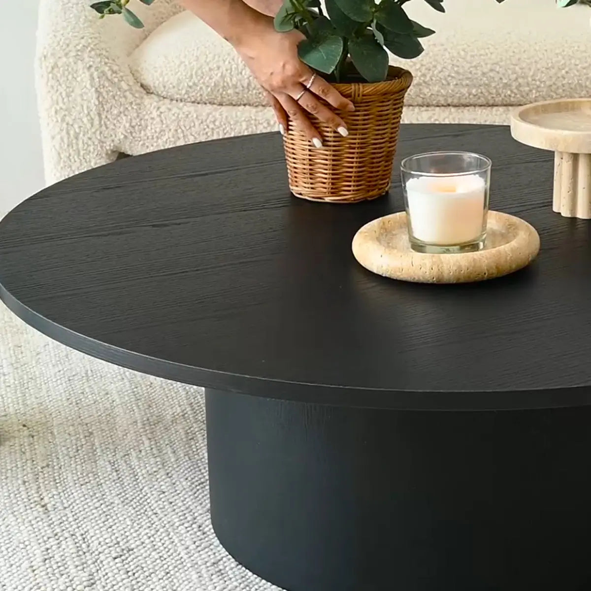 Dwen Modern Round Pedestal Coffee Table with beige textured sofa and light woven rug in living room.