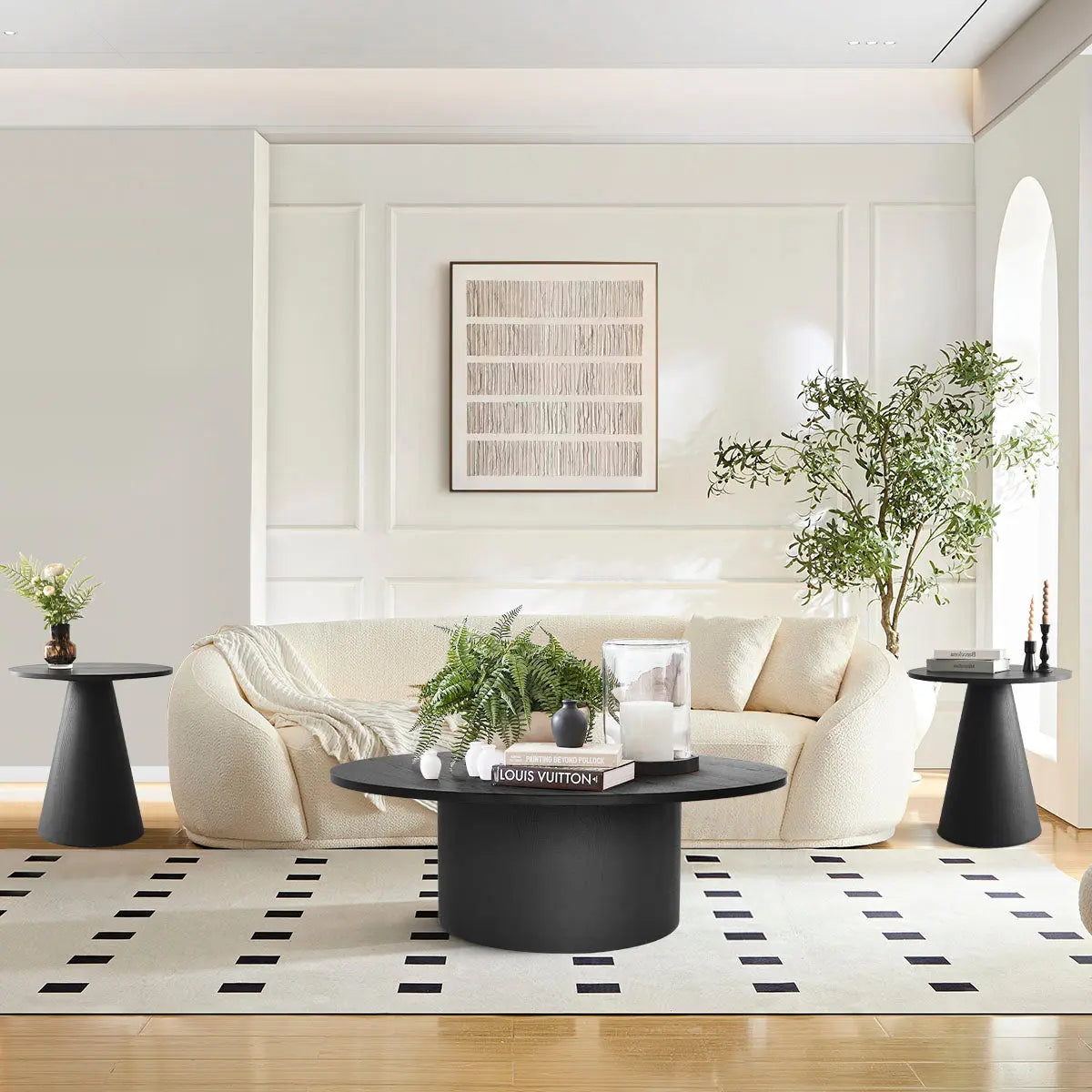 Dwen Black Round Table Set in living room with cream sofa, white wall, and light wood flooring.