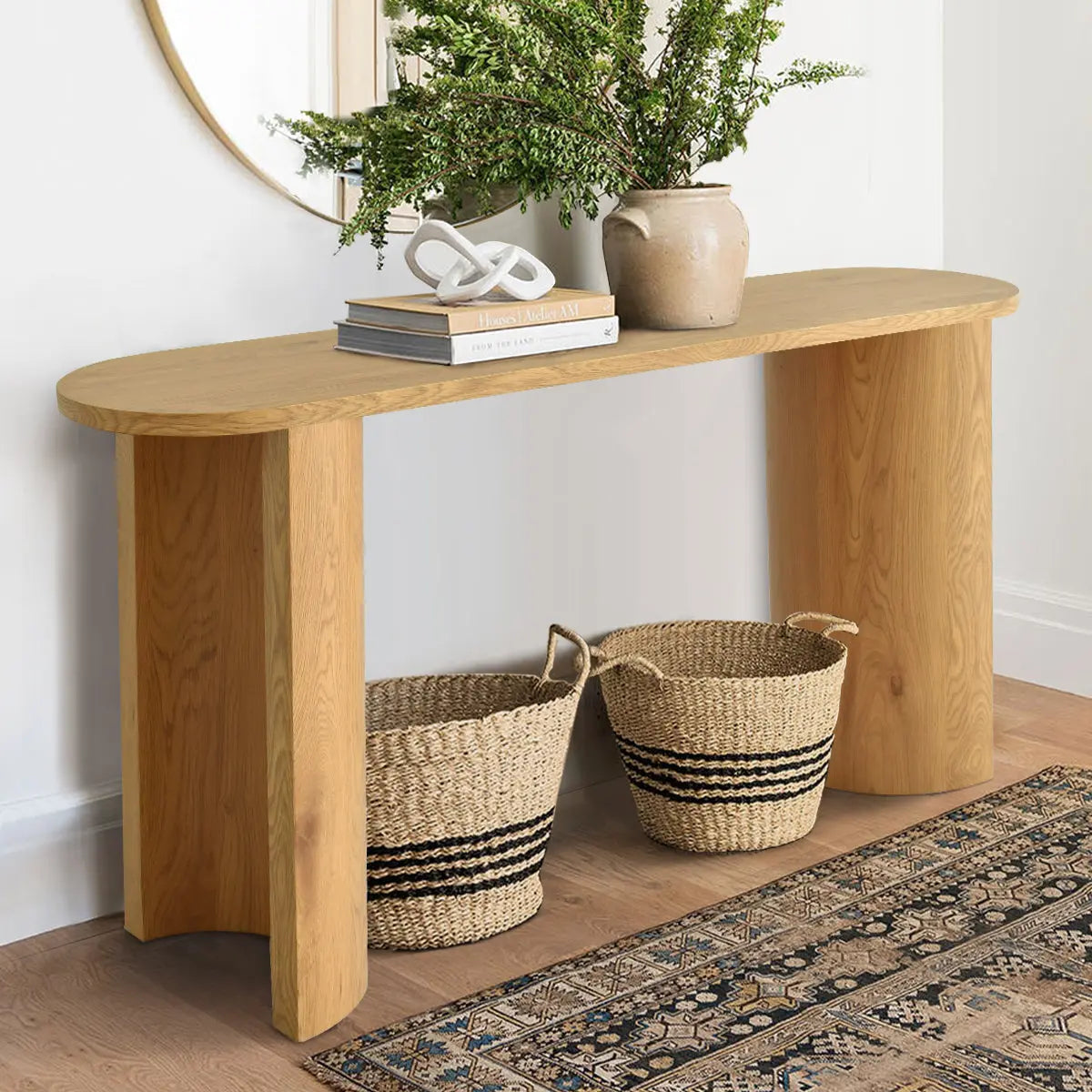 Dwen Modern Oval Console Table in bright room with wall mirror, wicker baskets, and patterned rug.