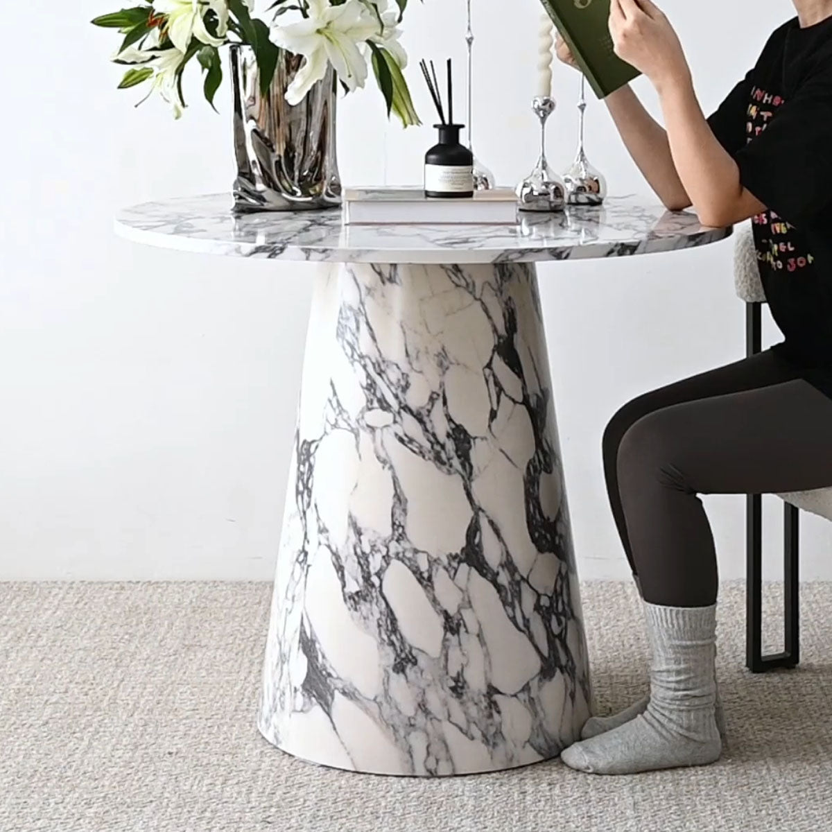 Dwen Modern Marble Round Pedestal Dining Table with gray chair, neutral carpet flooring, white wall.