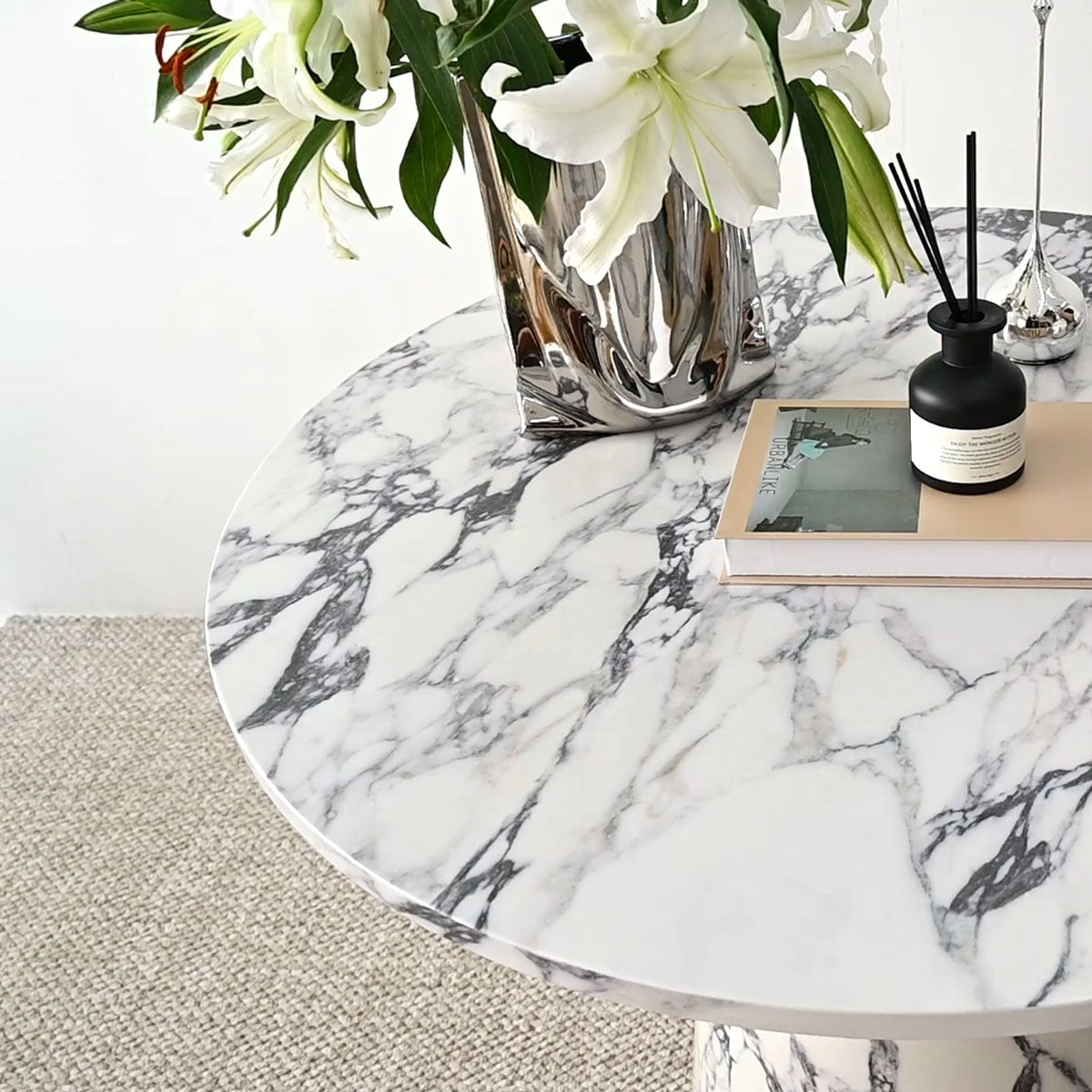 Dwen Modern Marble Round Pedestal Dining Table with elegant marble top on textured rug flooring.