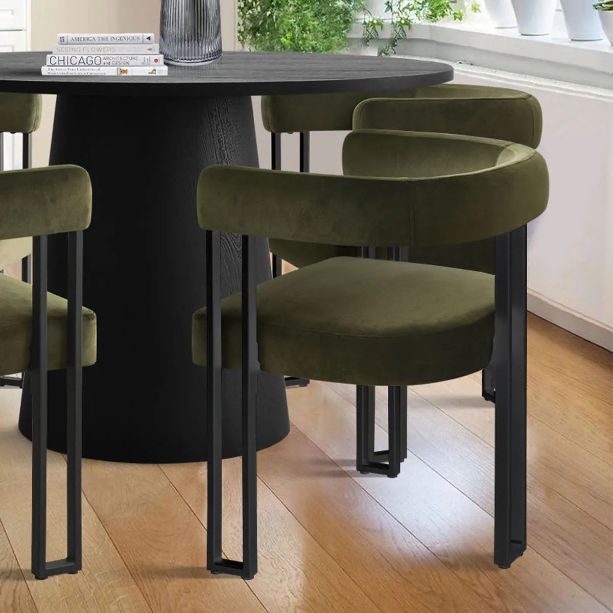 Dwen & Mia dining table set with green velvet chairs, light wooden flooring, white wall background.