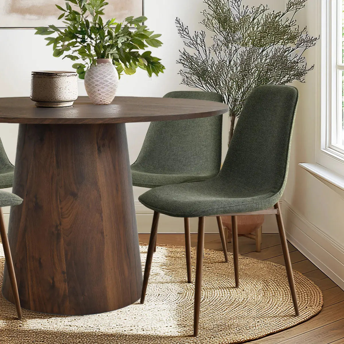 Dwen & Oslo dining table set in modern room; features green chairs, round table, woven rug.