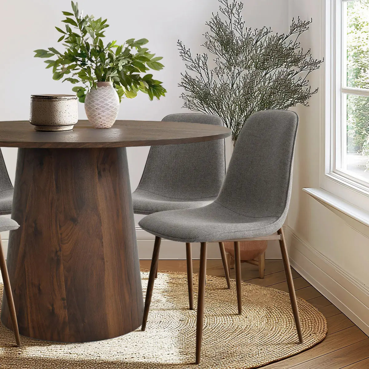 Dwen & Oslo dining table set with gray chairs, wood flooring, beige wall, and natural decor.