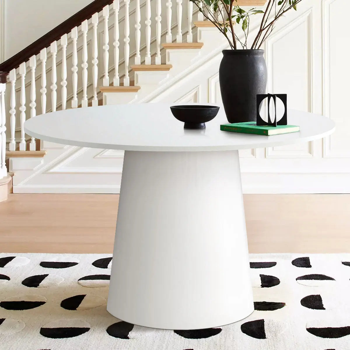 Dwen Modern Round Pedestal Dining Table in elegant room with light wood flooring and staircase backdrop.