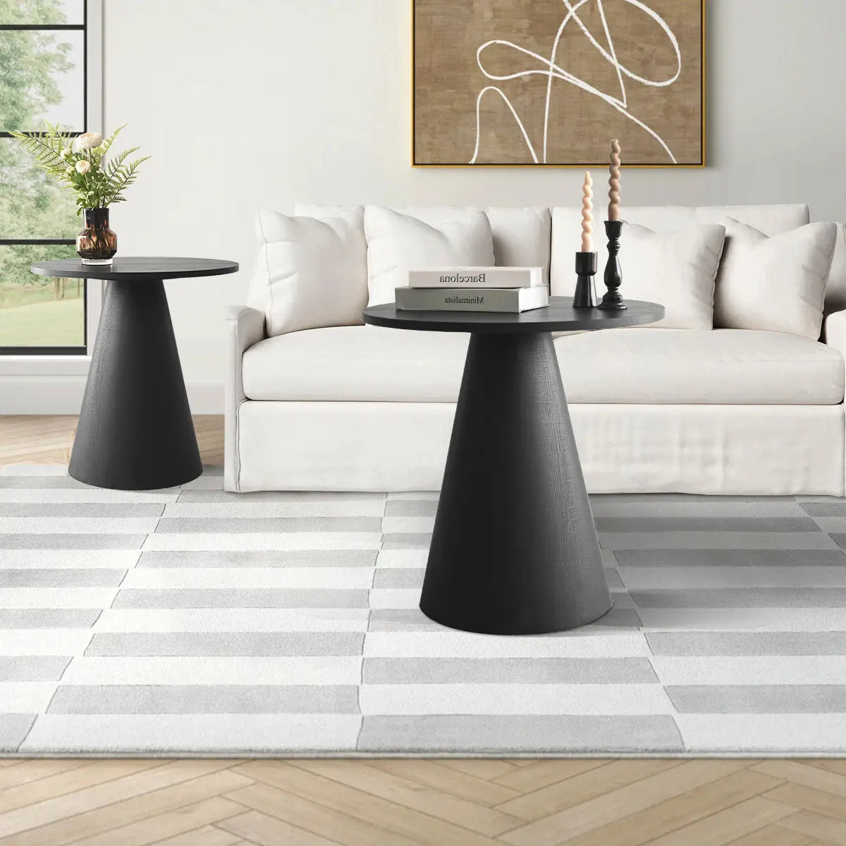 Dwen Modern Black Round Side Table, light sofa, herringbone floor, striped rug, abstract wall art.