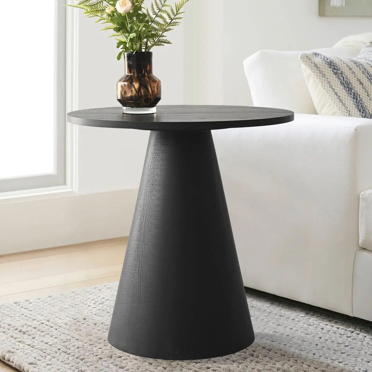 Dwen 24" modern black round side table in living room, white sofa, light wood flooring, gray rug.