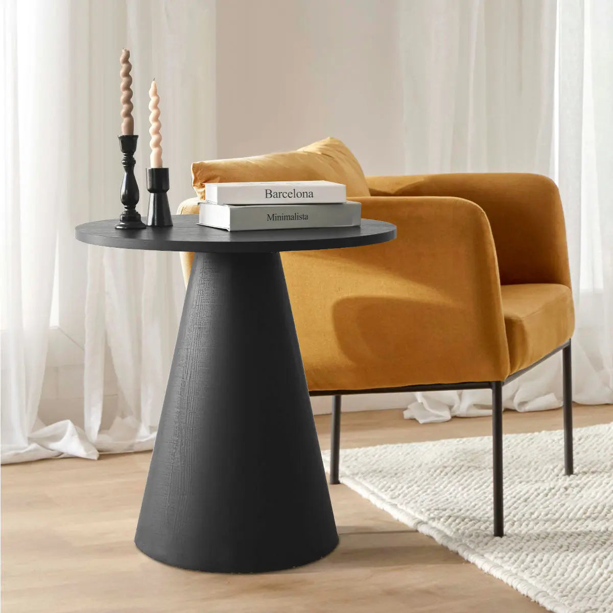 Dwen Modern Black Round Side Table with mustard armchair on light hardwood floor in living room.