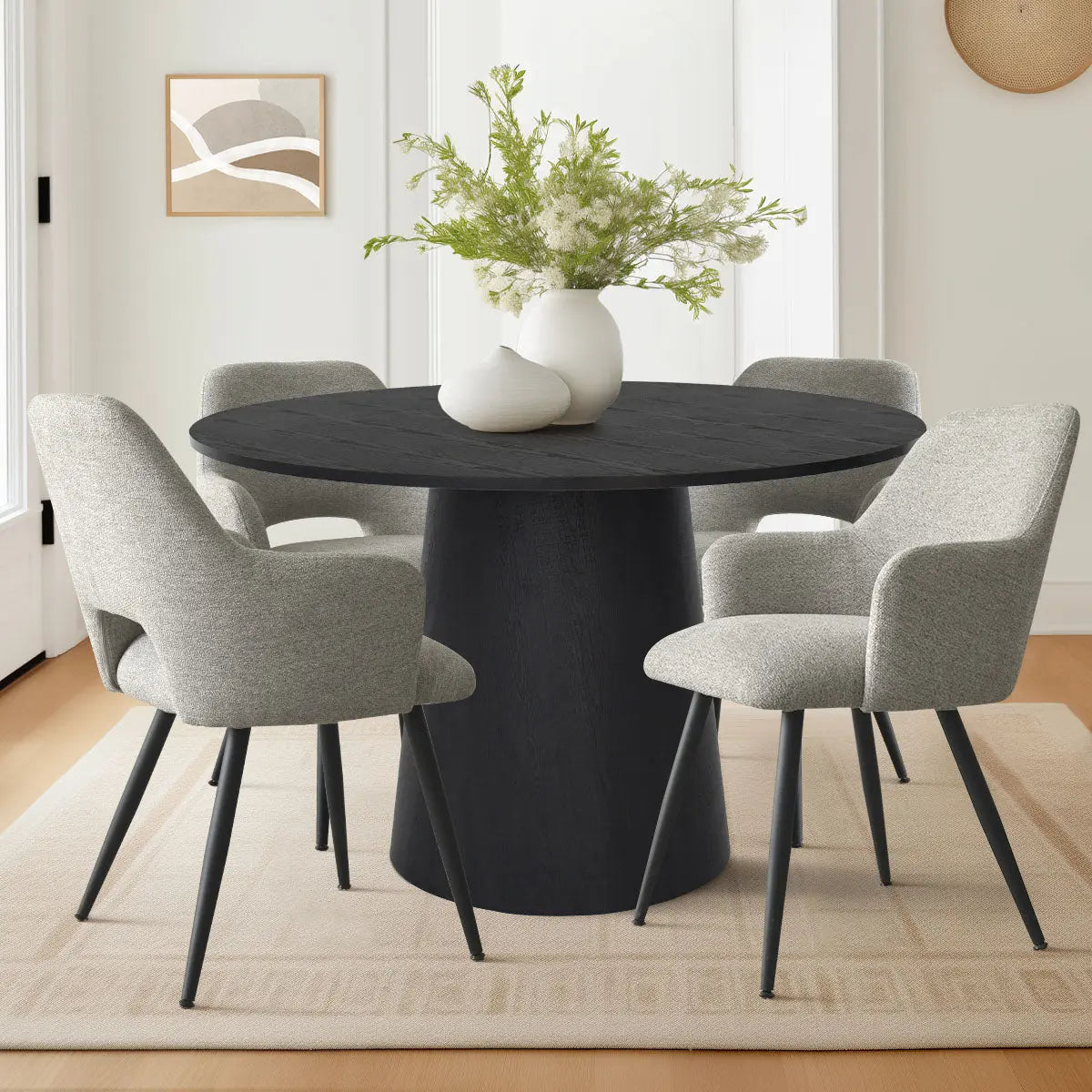 Dwen & Edwin Black Round Dining Table Set with gray chairs, in a modern dining room, beige rug.