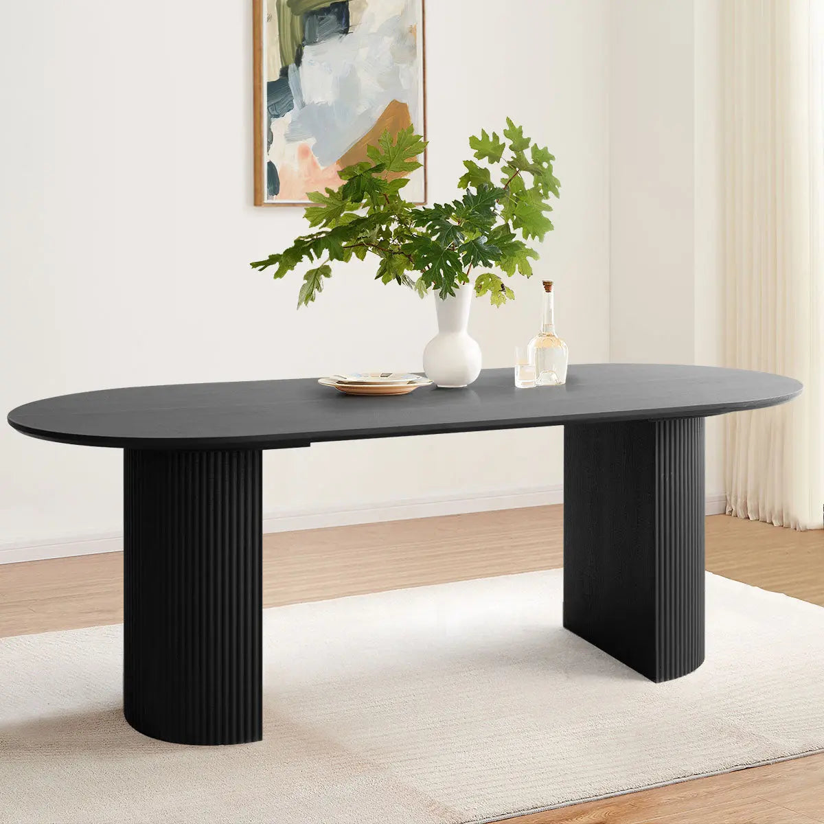 Dwen oval dining table with Roman pillars in modern room; light walls, wood floors, abstract art.