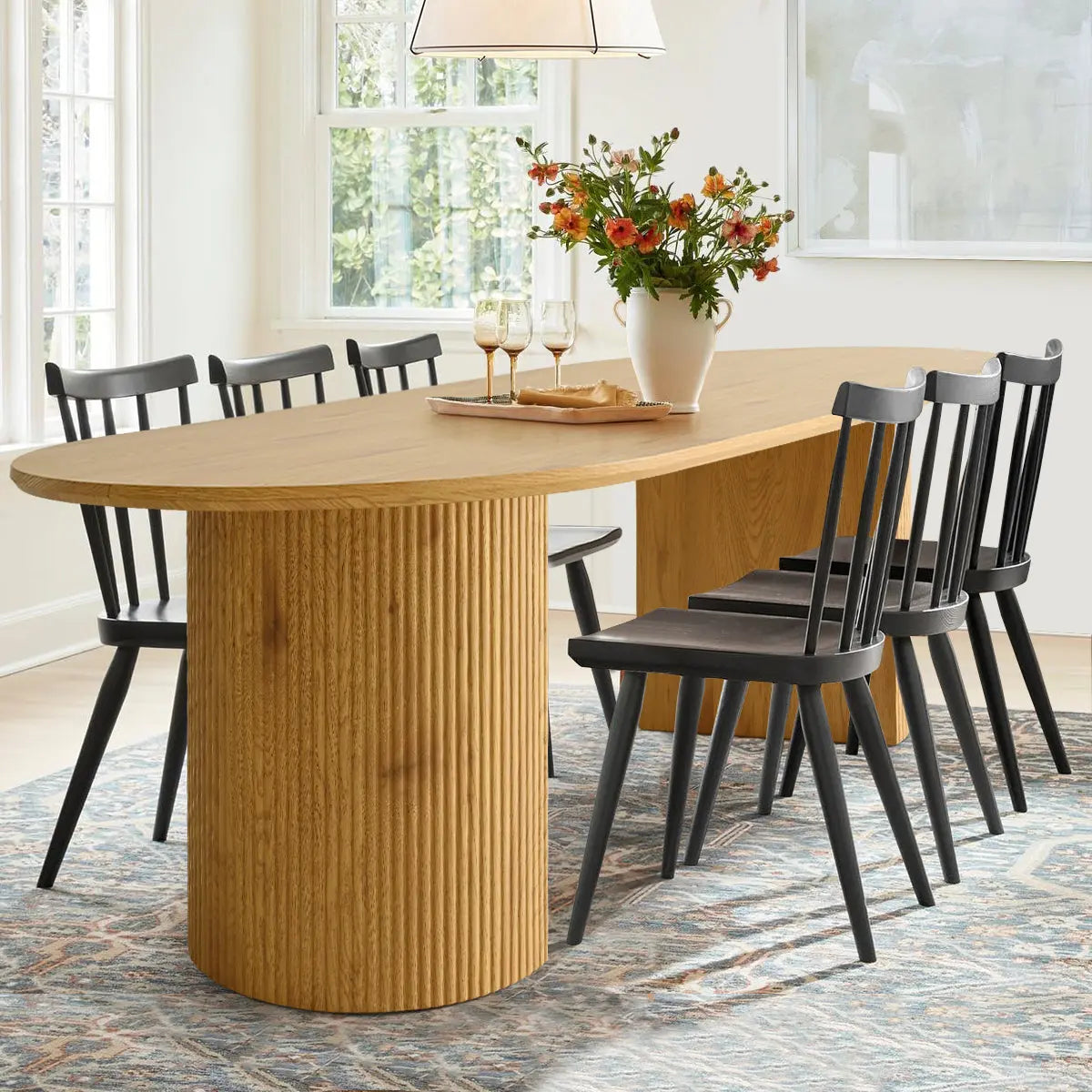 Dwen Modern Oval Dining Table with Roman Pillar, black chairs, modern rug, bright dining room.