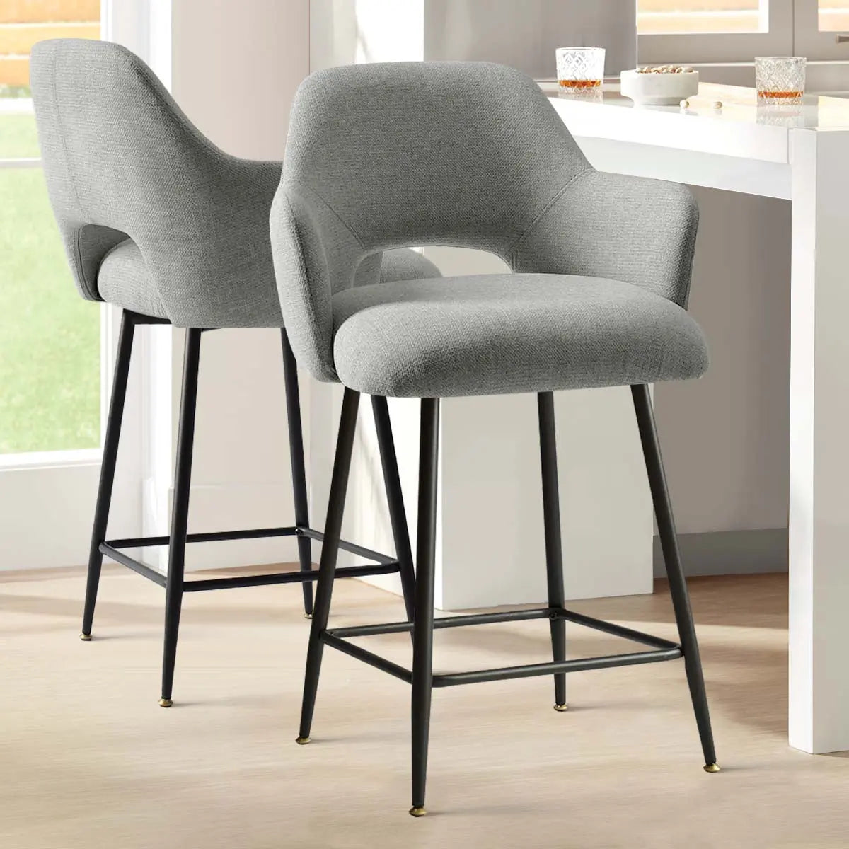 Edwin 25.5" modern upholstered stools with arms, light gray, black legs, in bright kitchen space.