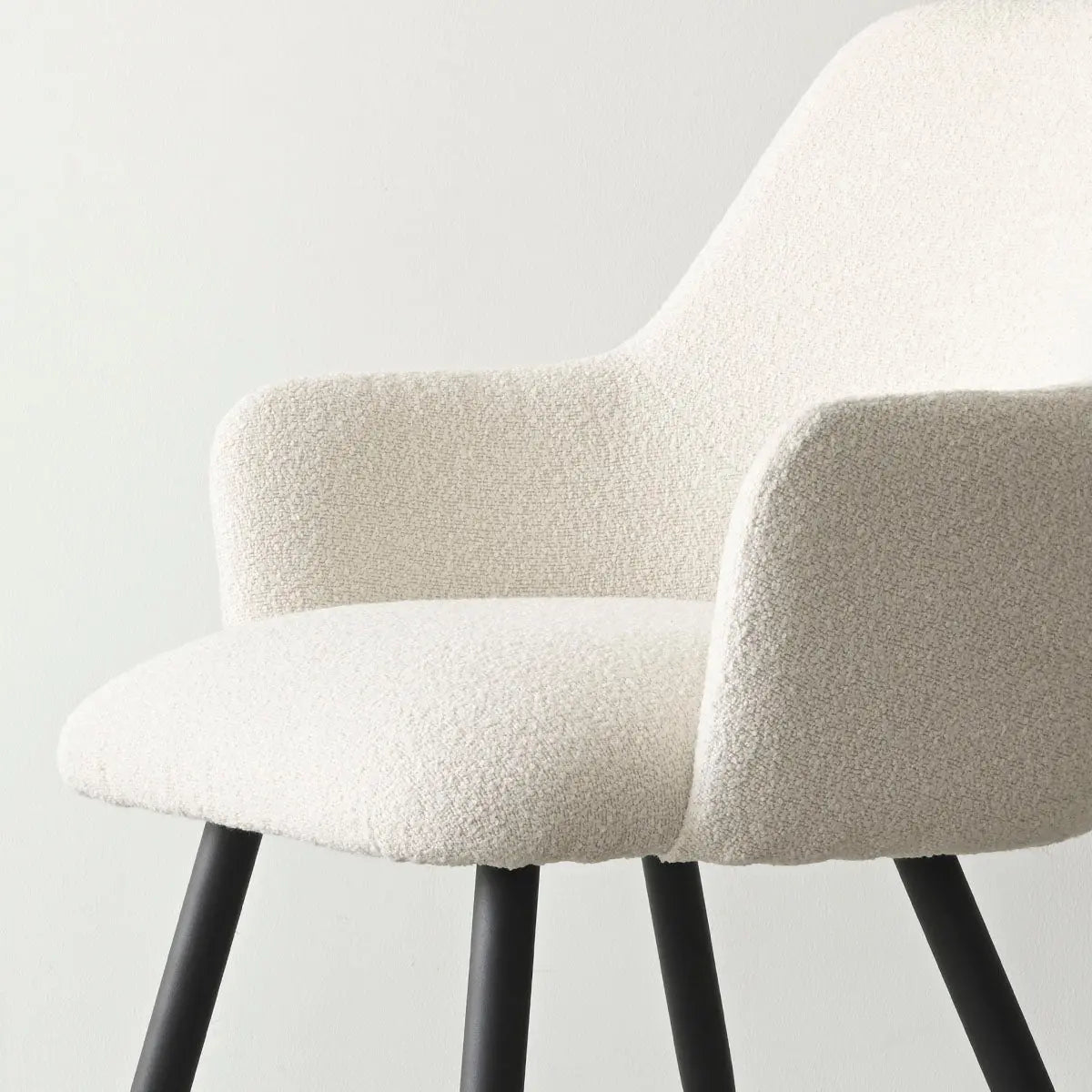 Edwin Modern Upholstered Dining Chair with Arms in neutral room setting, white wall, black legs.