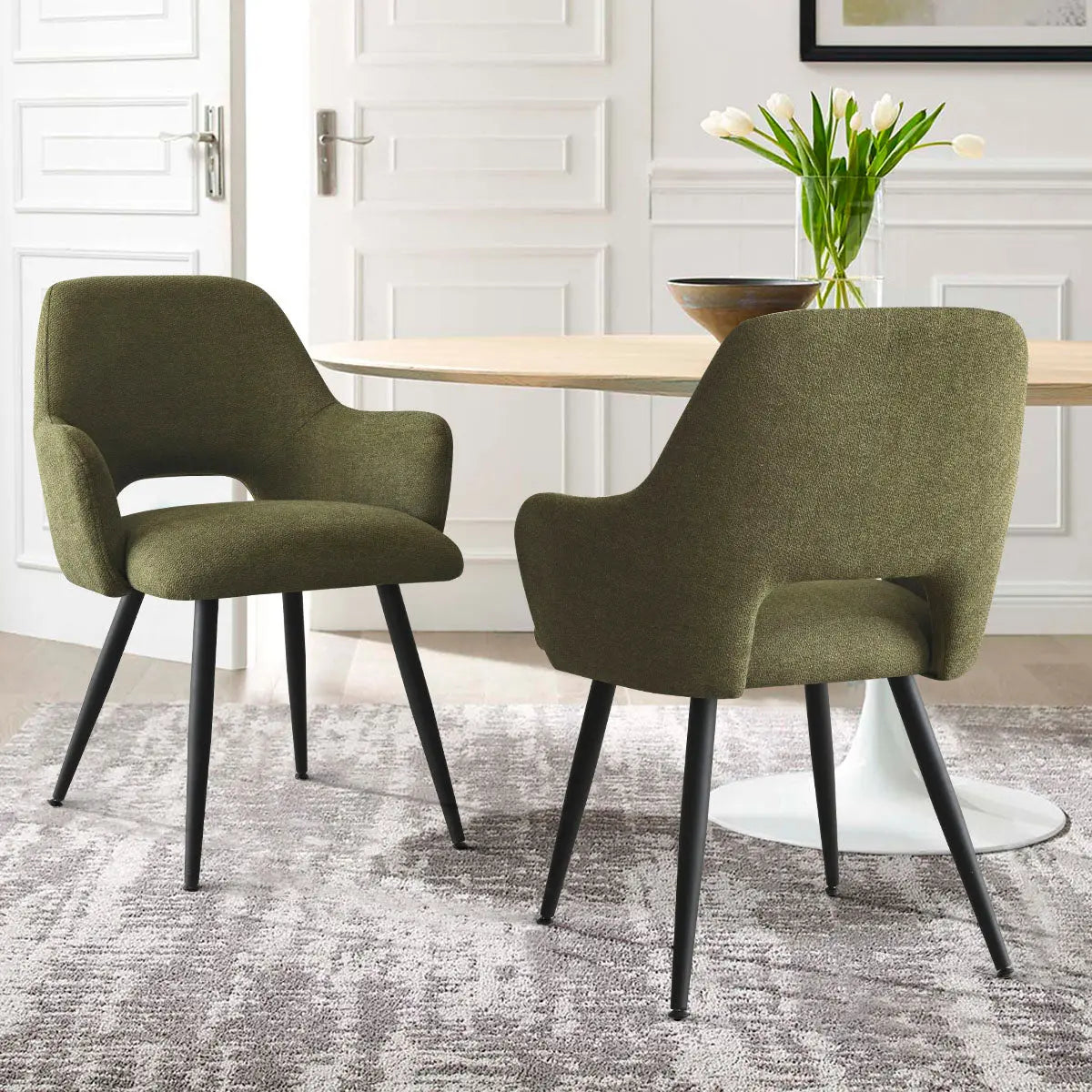 Edwin Modern Upholstered Dining Chair, green fabric, black legs, next to round table, in dining room.