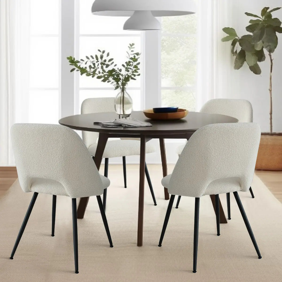 Edwin dining chairs with metal legs, modern round table, beige rug, white curtains, indoor plant.