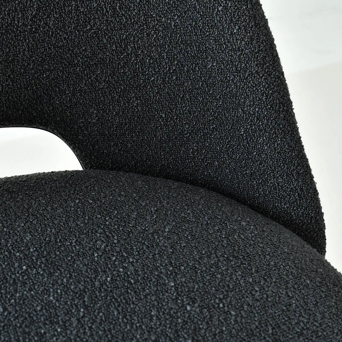 Close-up of black upholstery texture on Edwin dining chair with modern metal legs in contemporary setting.